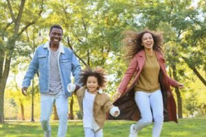 young smiling parents with their daughter walking in the park